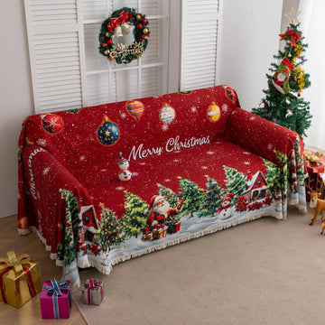 Festive red Christmas-themed sofa cover featuring decorated ornaments, snowflakes, snowy pine trees, a cheerful snowman, Santa Claus with gifts, and a cozy snow-covered house with poinsettias in the foreground.