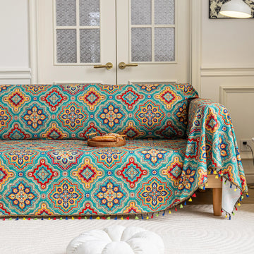 Colorful sofa cover with vibrant Moroccan-style geometric patterns in teal, red, yellow, and blue, finished with multicolor tassel trim.