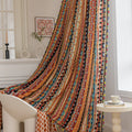 A vibrant curtain with a striking pattern of colorful stripes, featuring geometric shapes in red, orange, yellow, blue, and black. The curtain is adorned with playful tassels along the edges, adding a lively touch to the space.
