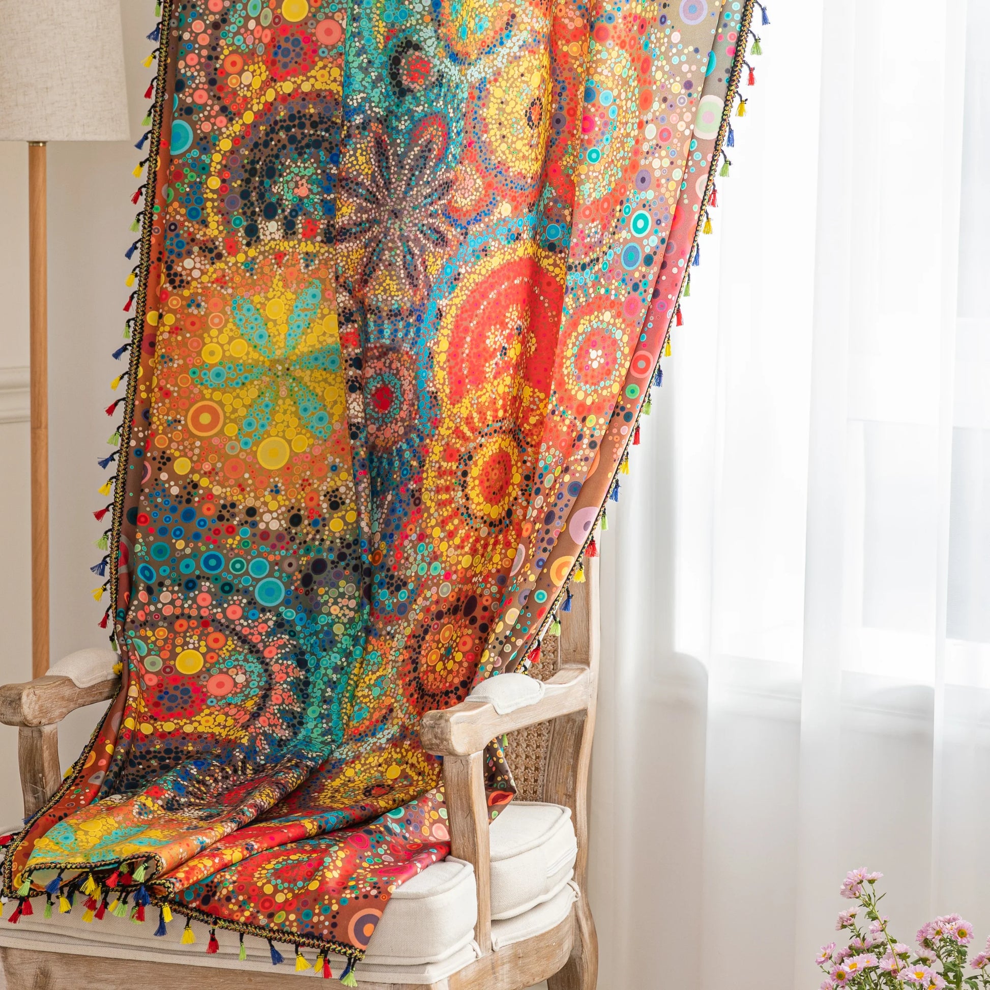 A colorful bohemian curtain with vibrant circular patterns in red, brown, blue, and yellow, decorated with multicolor tassels and braided trim, adding an artistic and lively touch to home décor.