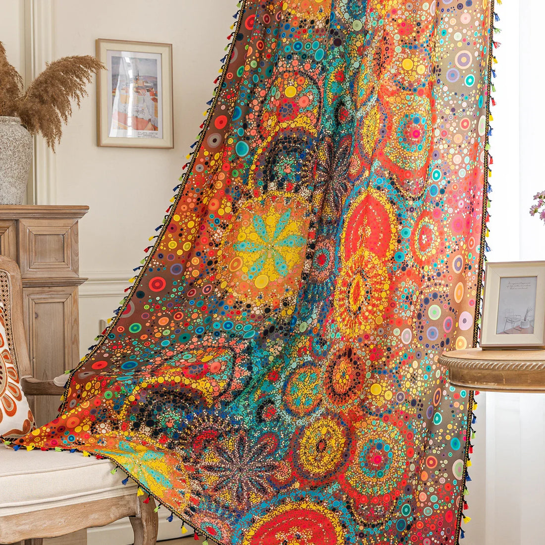 A colorful bohemian curtain with vibrant circular patterns in red, brown, blue, and yellow, decorated with multicolor tassels and braided trim, adding an artistic and lively touch to home décor.