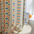 White curtain with bold geometric patterns in red, yellow, and blue, featuring stripes, triangles, and star shapes for a vibrant, modern, and playful home decor style.