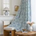 Elegant cream curtain fabric with intricate blue floral patterns, finished with decorative beige tassel trim for a classic, sophisticated look.