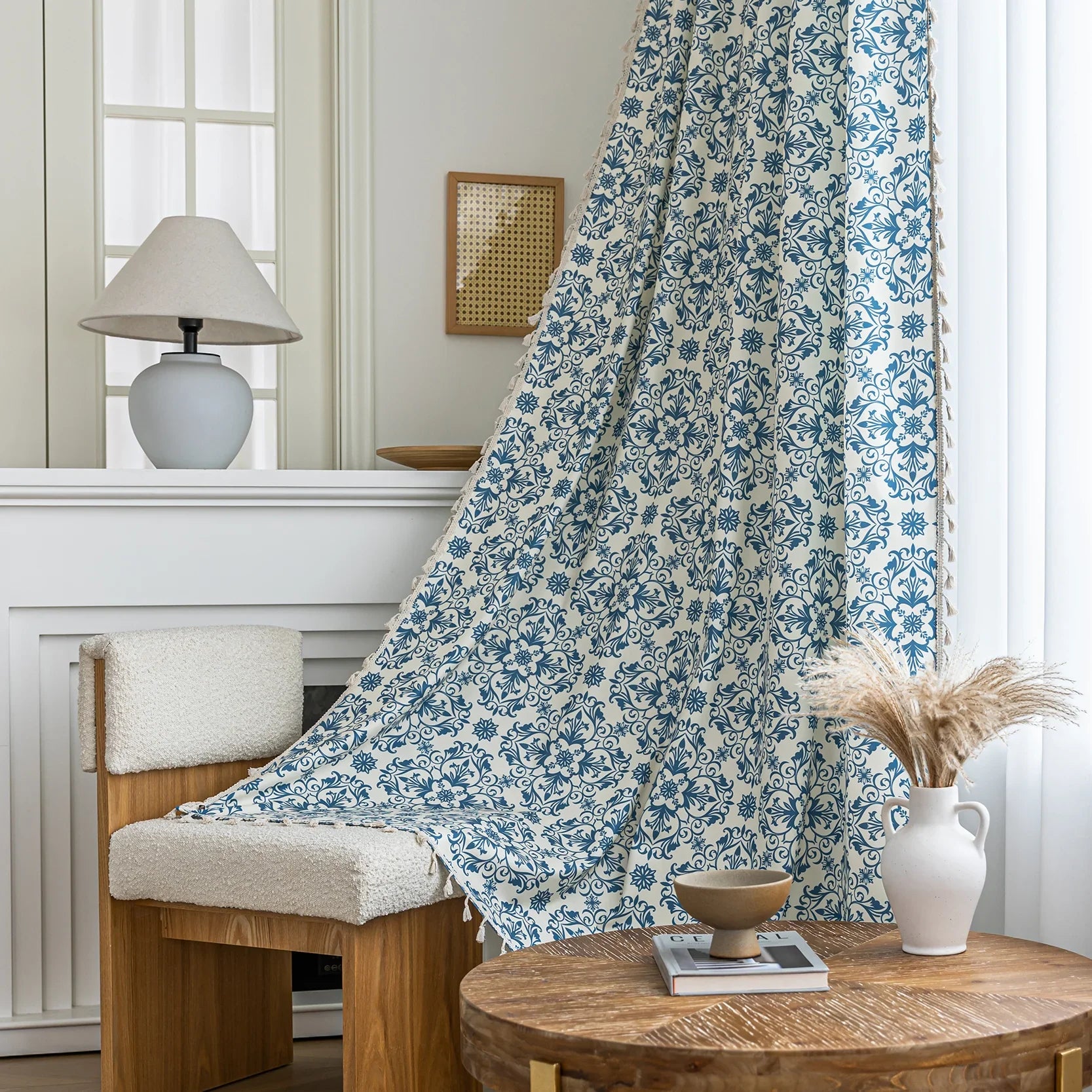 Elegant cream curtain fabric with intricate blue floral patterns, finished with decorative beige tassel trim for a classic, sophisticated look.