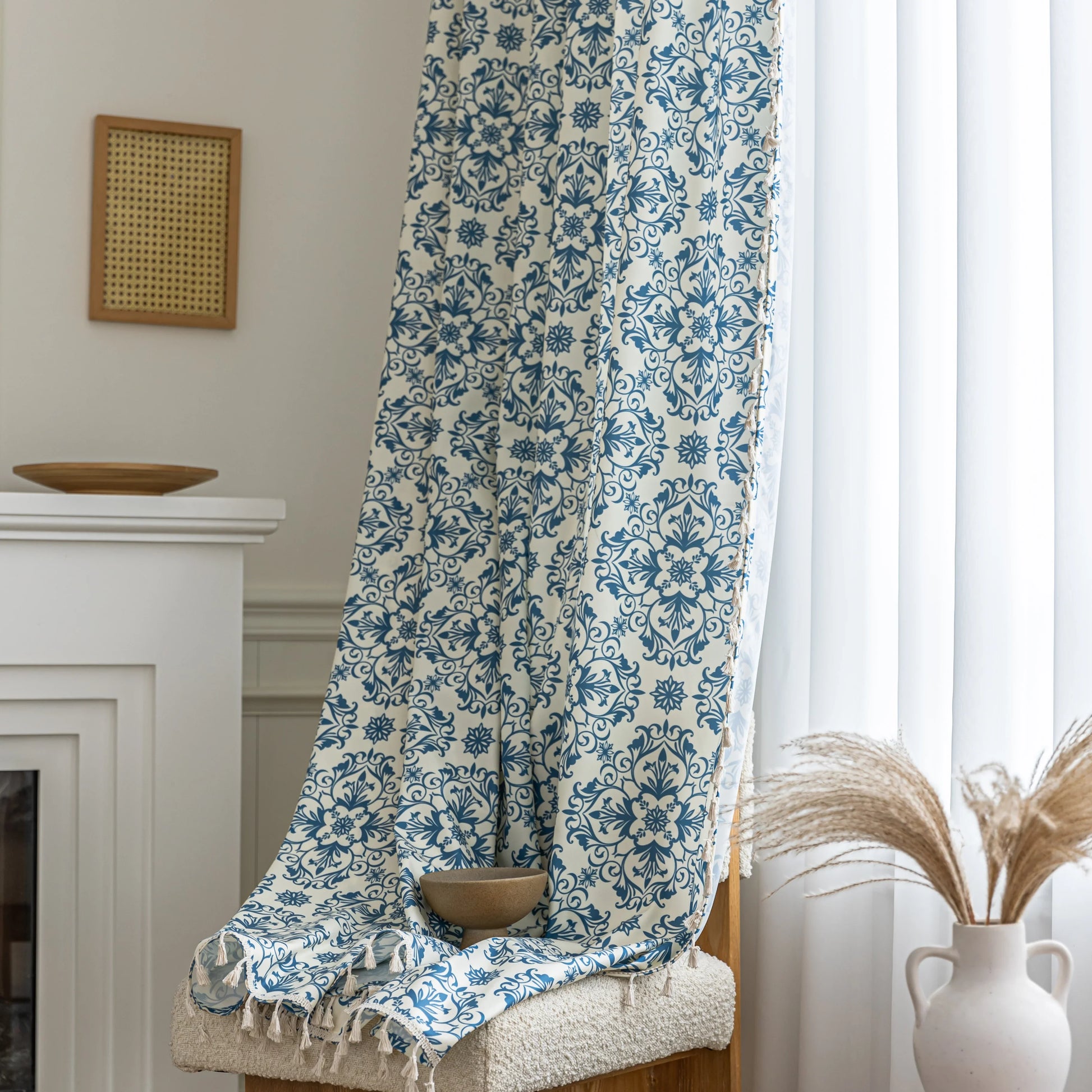 Elegant cream curtain fabric with intricate blue floral patterns, finished with decorative beige tassel trim for a classic, sophisticated look.