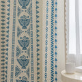 Cream curtain fabric with intricate blue tribal and geometric patterns, finished with decorative beige tassel trim for a stylish bohemian look.