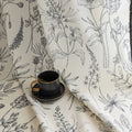 Cream curtains with black botanical print and black tassel trim.