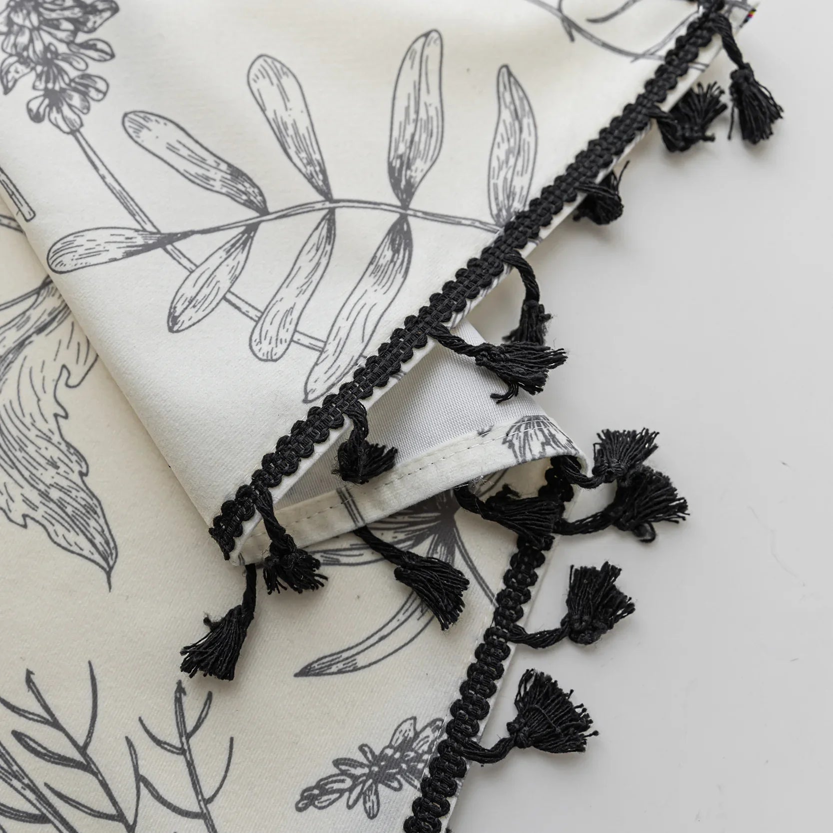 Cream curtains with black botanical print and black tassel trim.