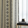 Close-up of cream curtain with bold black vertical tribal and geometric patterns, adding a modern bohemian touch to interior decor.