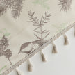 Close-up of beige curtain with bird and botanical print in brown and green, featuring decorative tassel trim for a rustic, nature-inspired look.