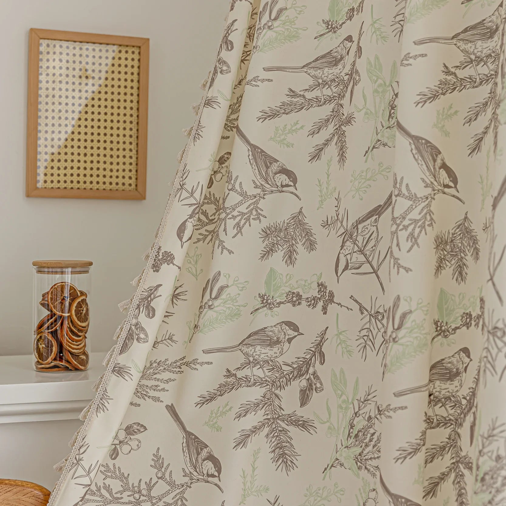 Beige curtain with bird and botanical print in brown and green, featuring decorative tassel trim for a rustic, nature-inspired look.