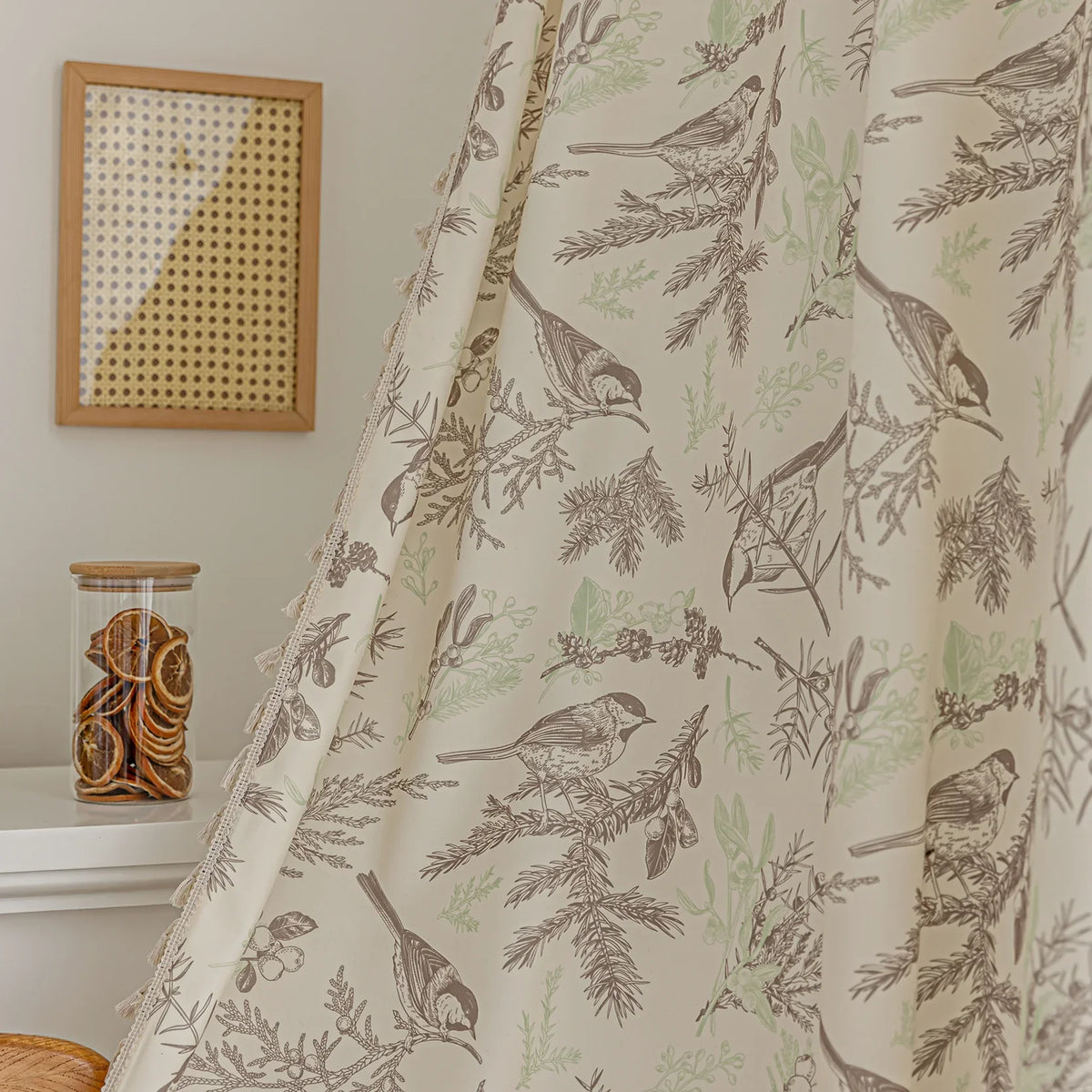 Beige curtain with bird and botanical print in brown and green, featuring decorative tassel trim for a rustic, nature-inspired look.