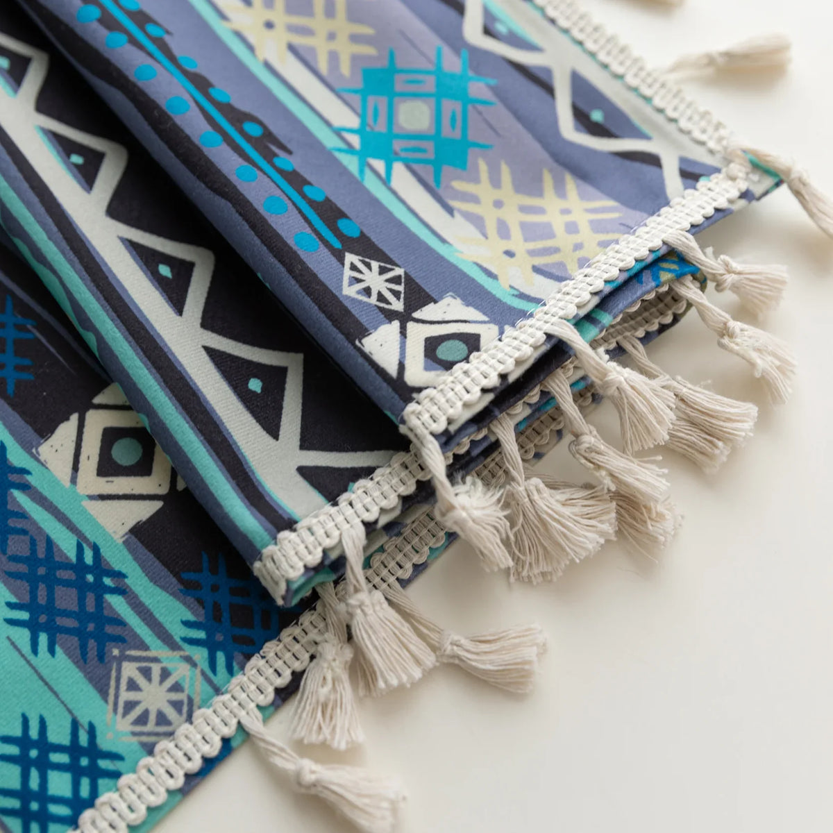 Close-up of blue geometric patterned curtain with tribal-inspired design, featuring white tassel trim for a bold and decorative accent.