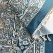 Close-up of blue and beige curtain fabric with intricate Persian-inspired floral patterns, featuring decorative tassel trim for an elegant and classic home d¨¦cor look.