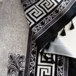 Close-up of black and white curtain fabric with Greek key pattern and floral accents, featuring decorative black tassel trim for a bold and elegant home d¨¦cor style.