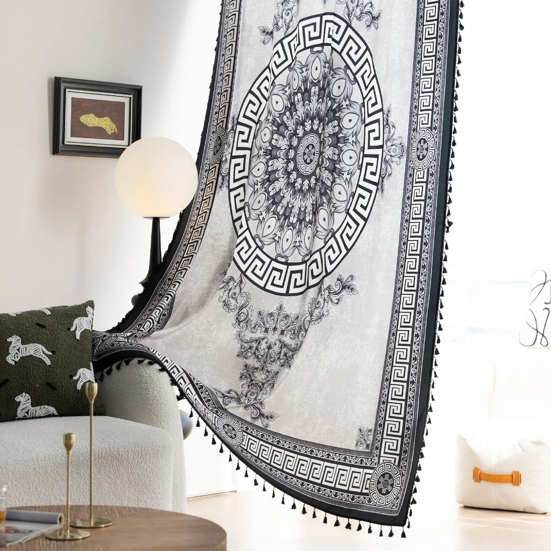 Black and white curtain fabric with Greek key pattern and floral accents, featuring decorative black tassel trim for a bold and elegant home décor style.