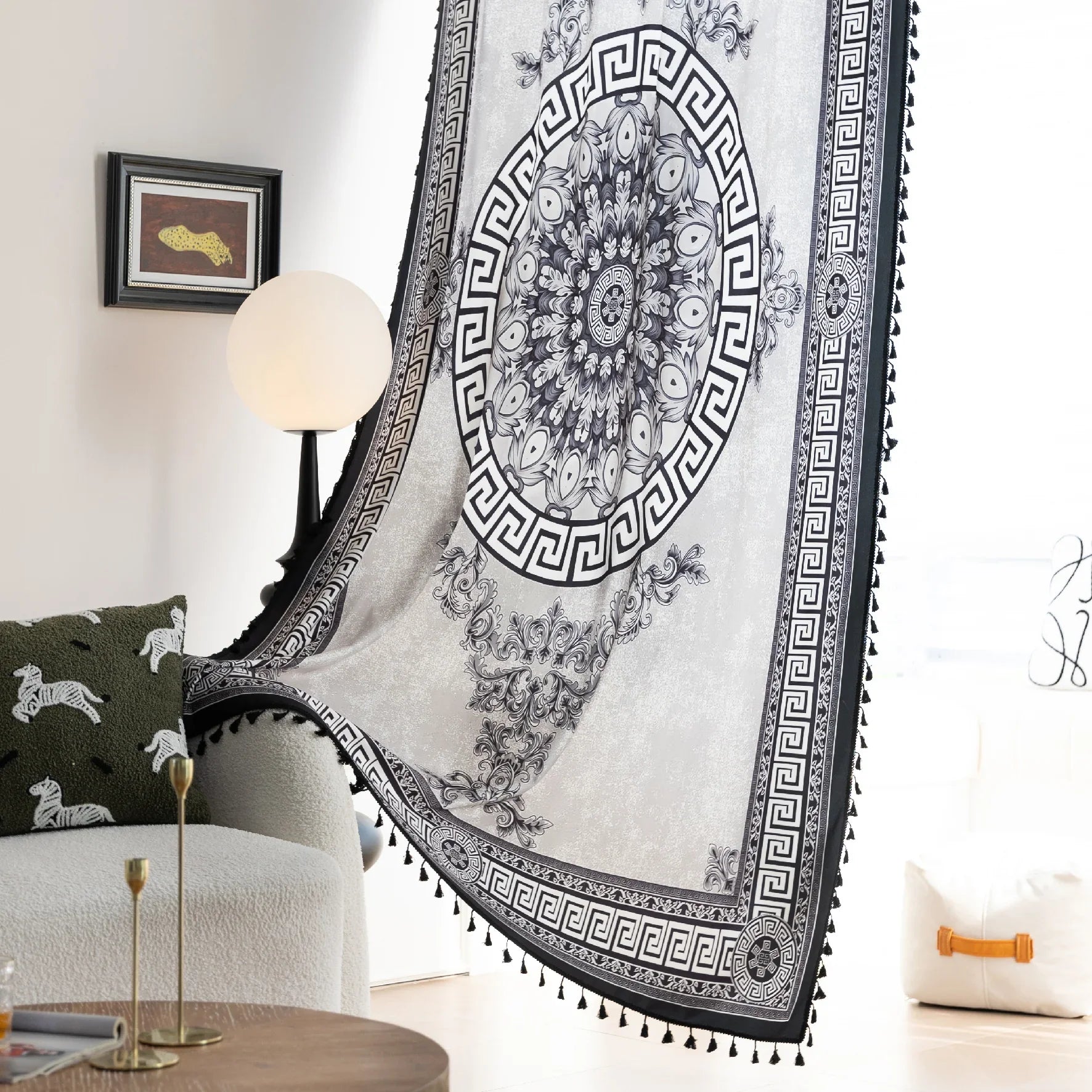 Black and white curtain fabric with Greek key pattern and floral accents, featuring decorative black tassel trim for a bold and elegant home décor style.