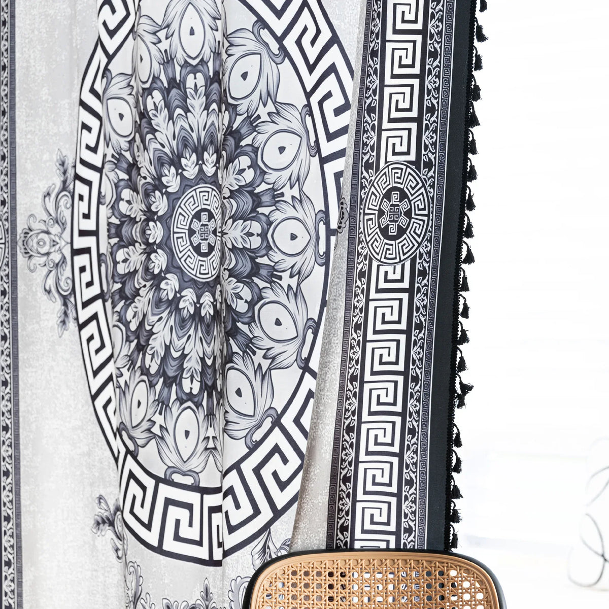 Black and white curtain fabric with Greek key pattern and floral accents, featuring decorative black tassel trim for a bold and elegant home d¨¦cor style.