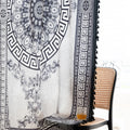 Black and white curtain fabric with Greek key pattern and floral accents, featuring decorative black tassel trim for a bold and elegant home décor style.