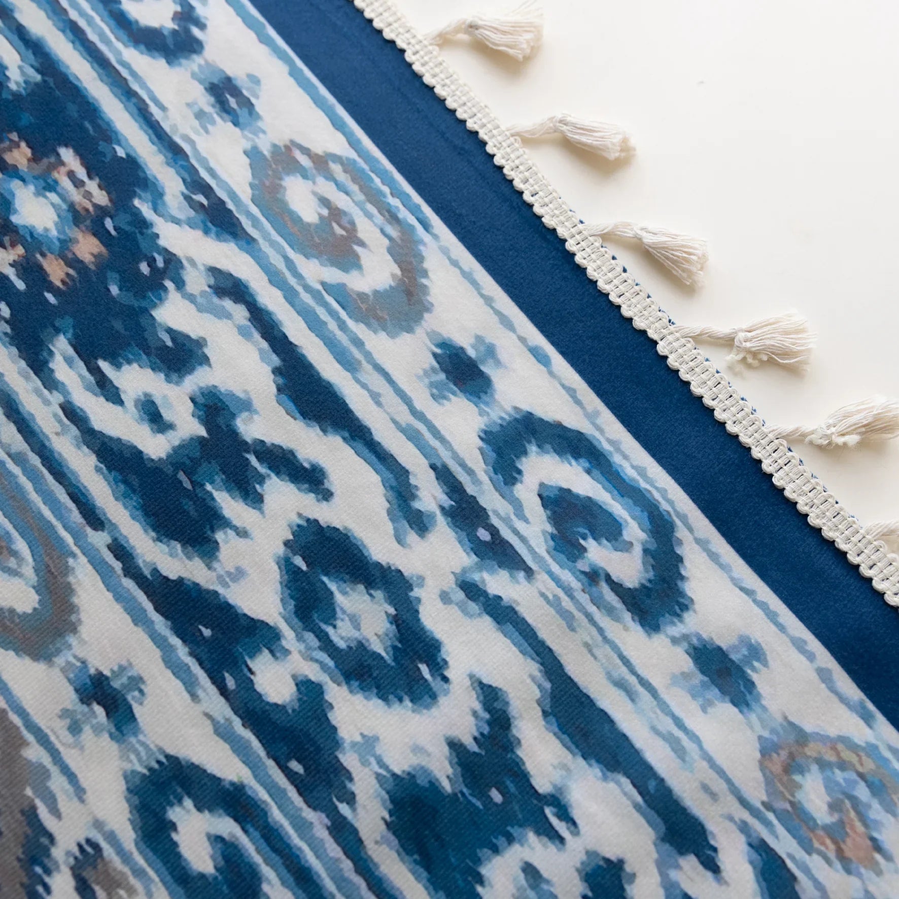 Blue and white curtain fabric with abstract watercolor-style pattern, accented by solid blue border and decorative white tassel trim for a coastal and artistic home décor look.
