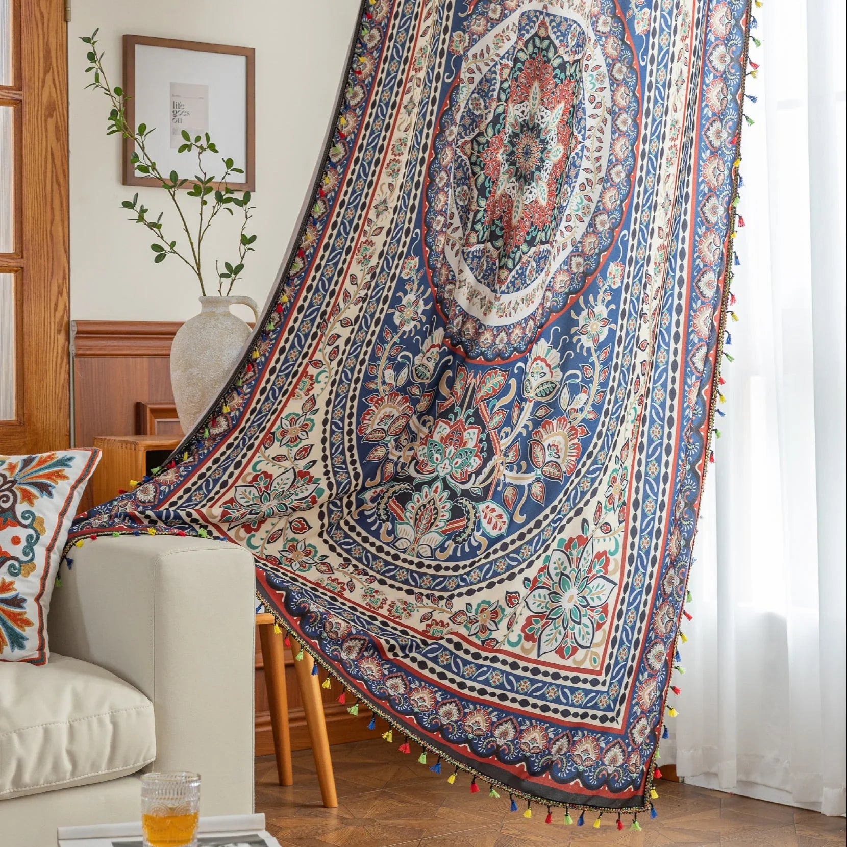Colorful bohemian curtain with intricate floral and medallion patterns in navy blue, red, green, and cream, adorned with multicolored tassels.