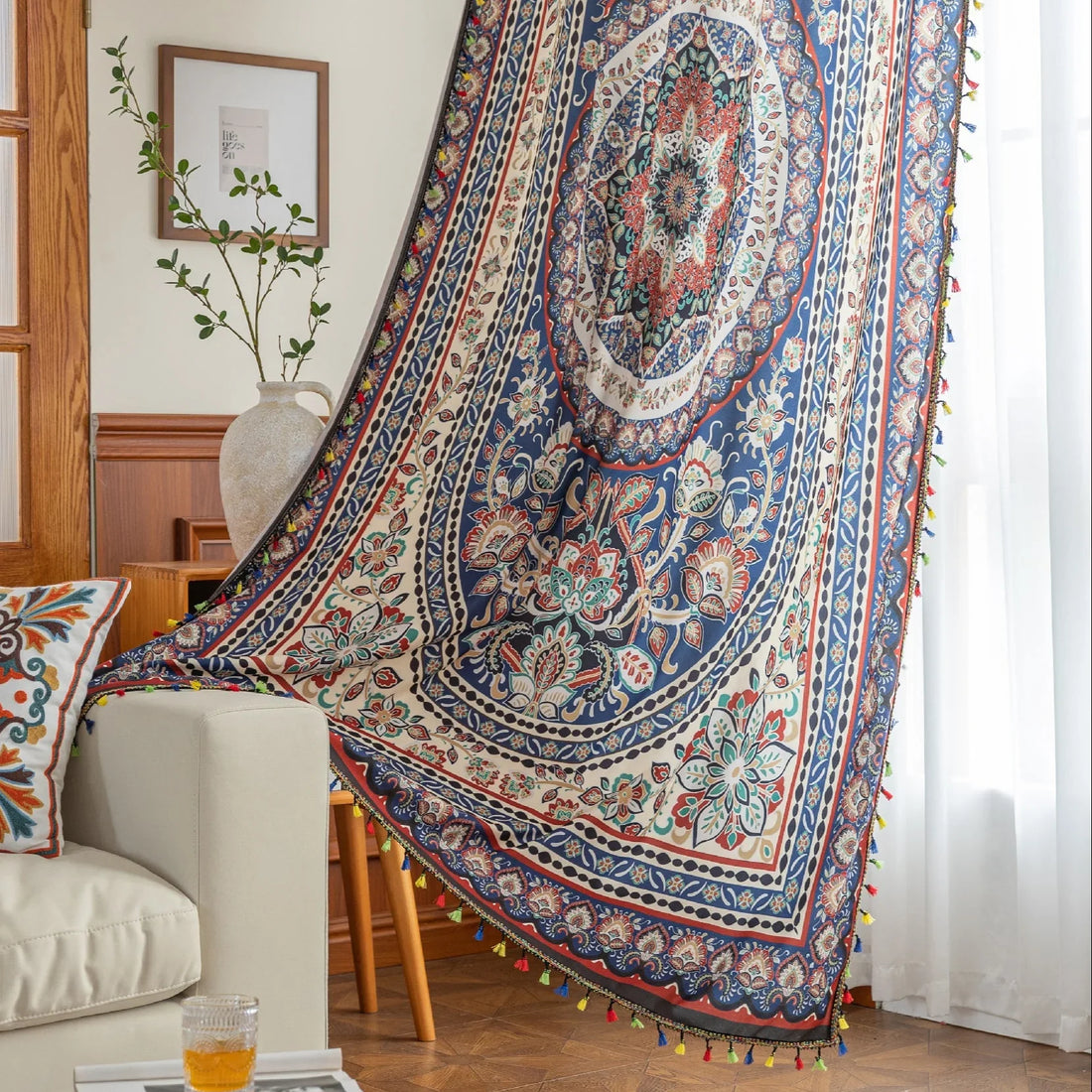 Colorful bohemian curtain with intricate floral and medallion patterns in navy blue, red, green, and cream, adorned with multicolored tassels.