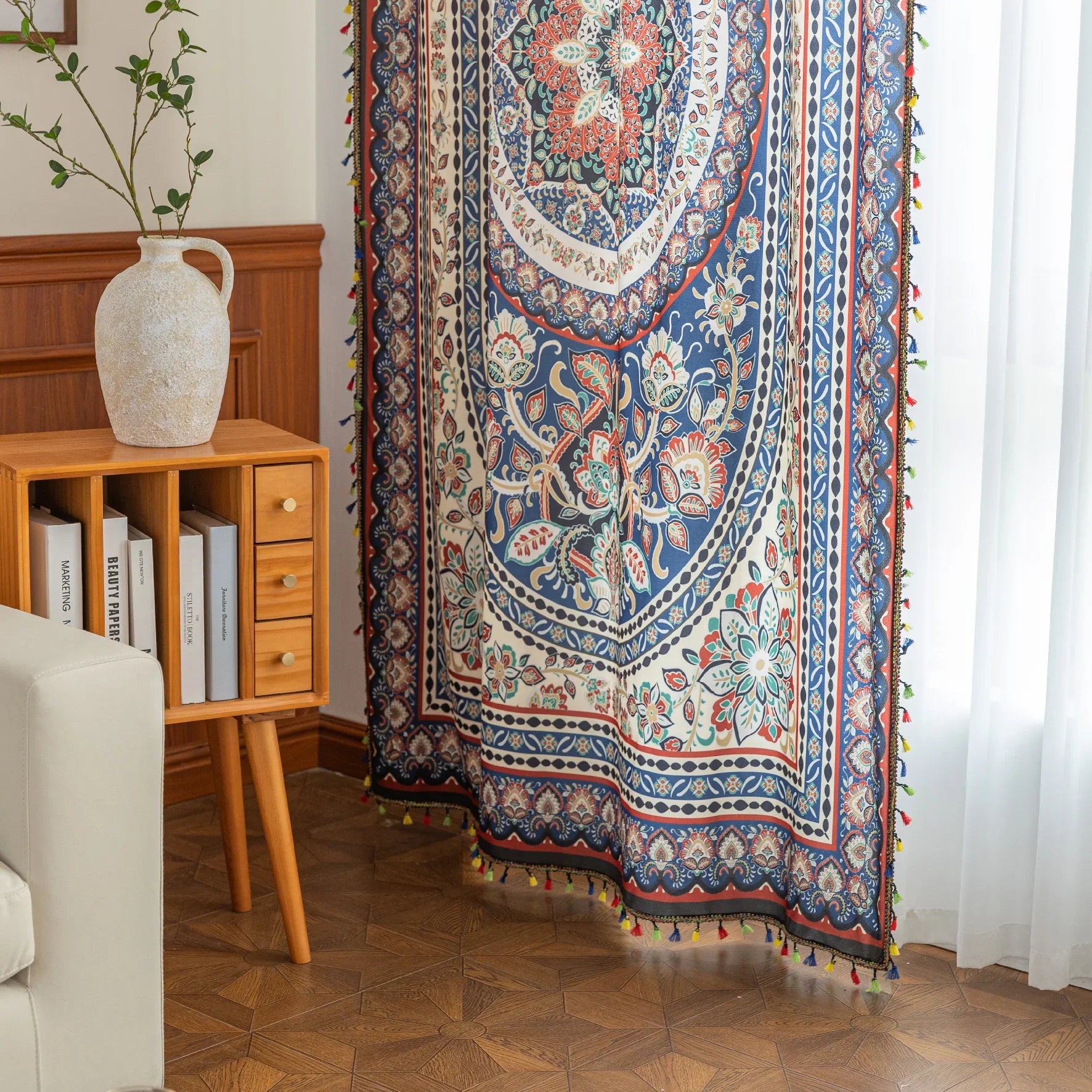 Colorful bohemian curtain with intricate floral and medallion patterns in navy blue, red, green, and cream, adorned with multicolored tassels.