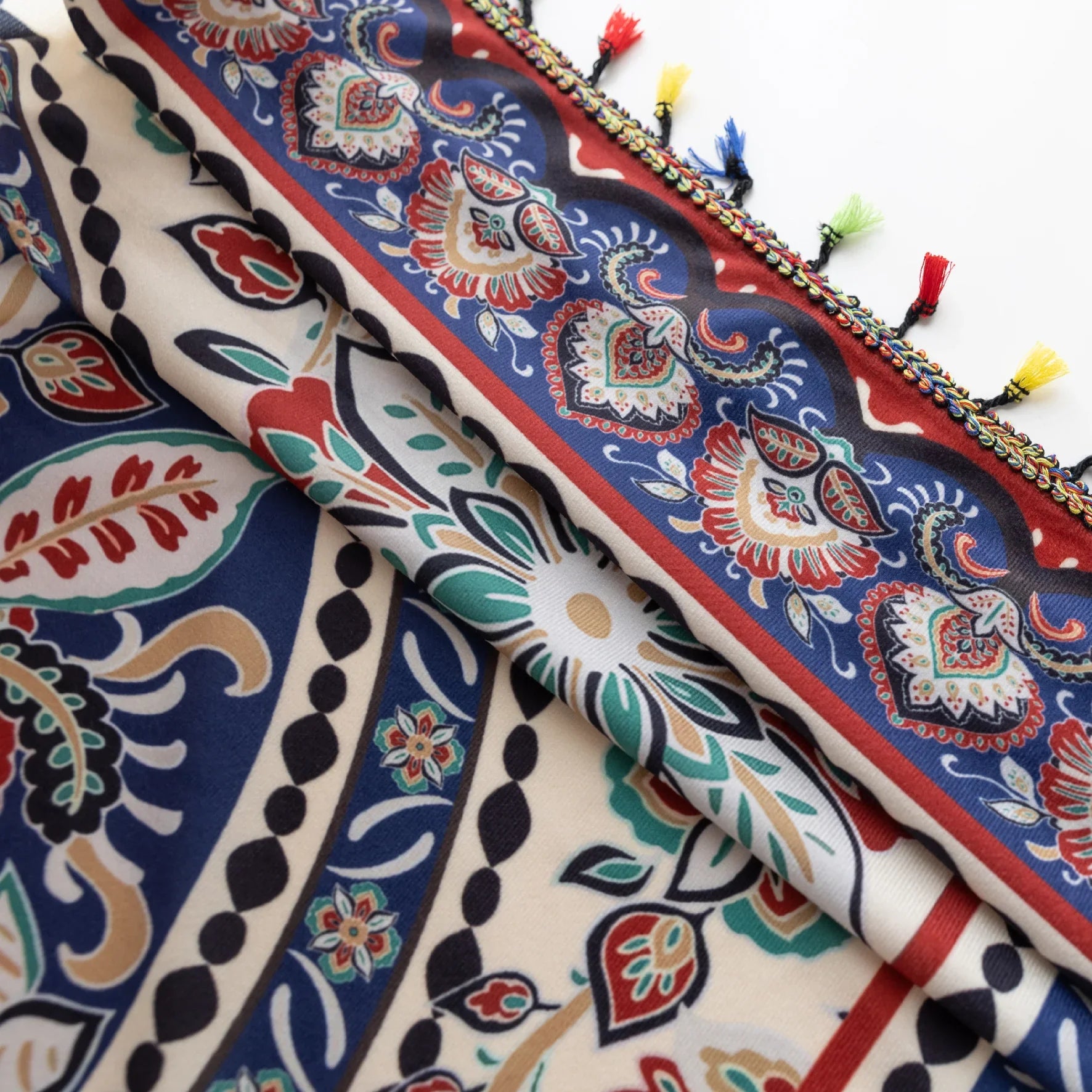 Colorful bohemian curtain with intricate floral and medallion patterns in navy blue, red, green, and cream, adorned with multicolored tassels.