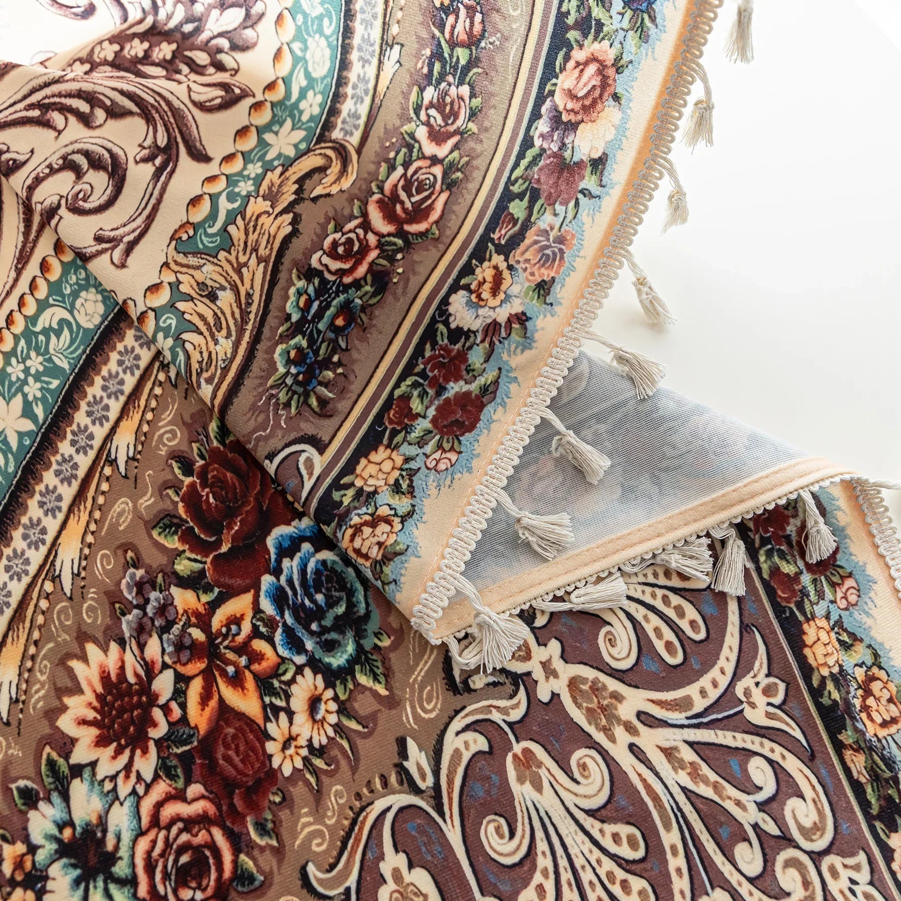 Close-up of a luxurious curtain with intricate floral and paisley patterns in rich brown, teal, and burgundy tones, adorned with delicate tassel trim for an elegant, classic home décor style.