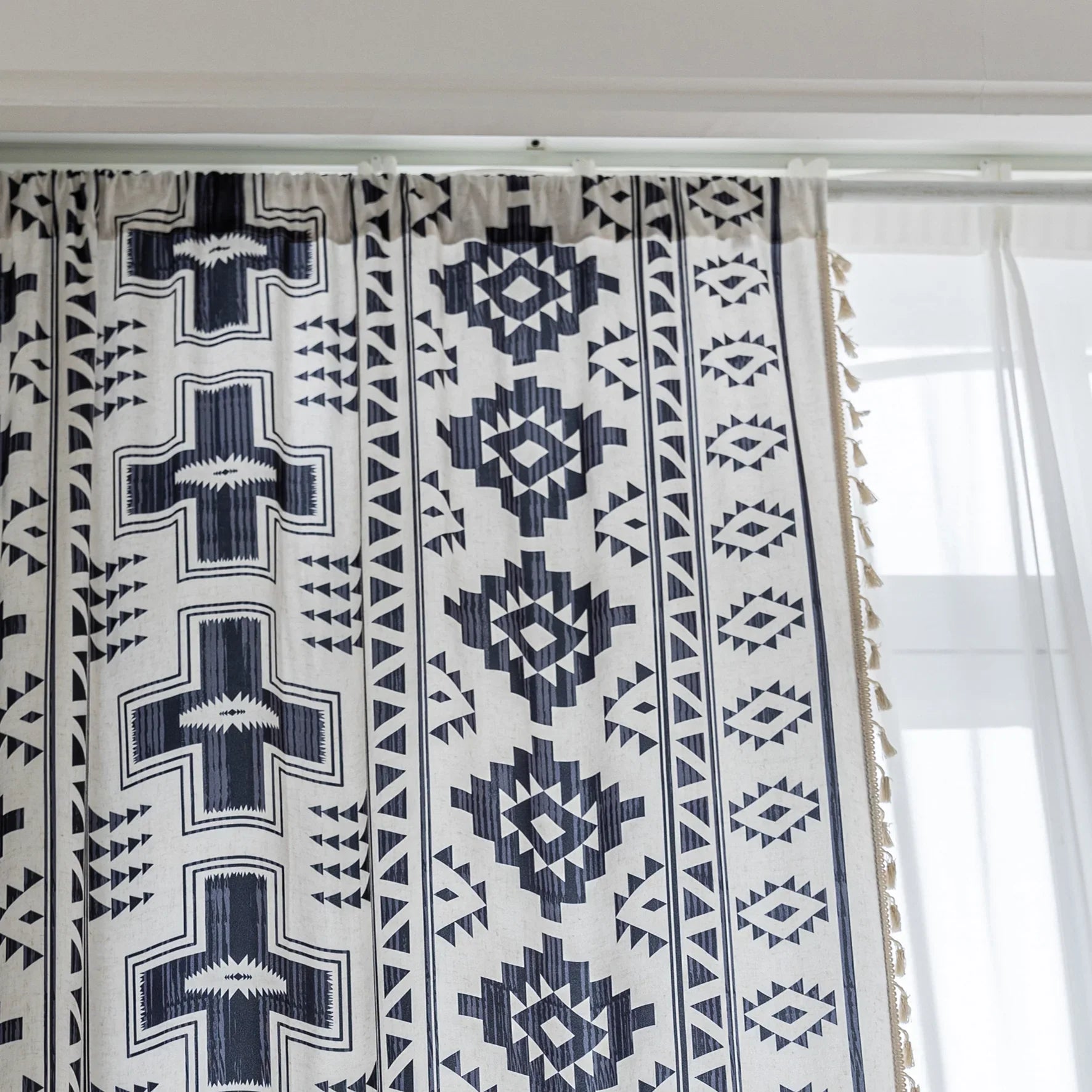 Stylish bohemian curtain featuring bold black geometric and cross patterns on a neutral background, accented with decorative tassel trim — perfect for adding a modern tribal touch to your living room, bedroom, or eclectic home décor.