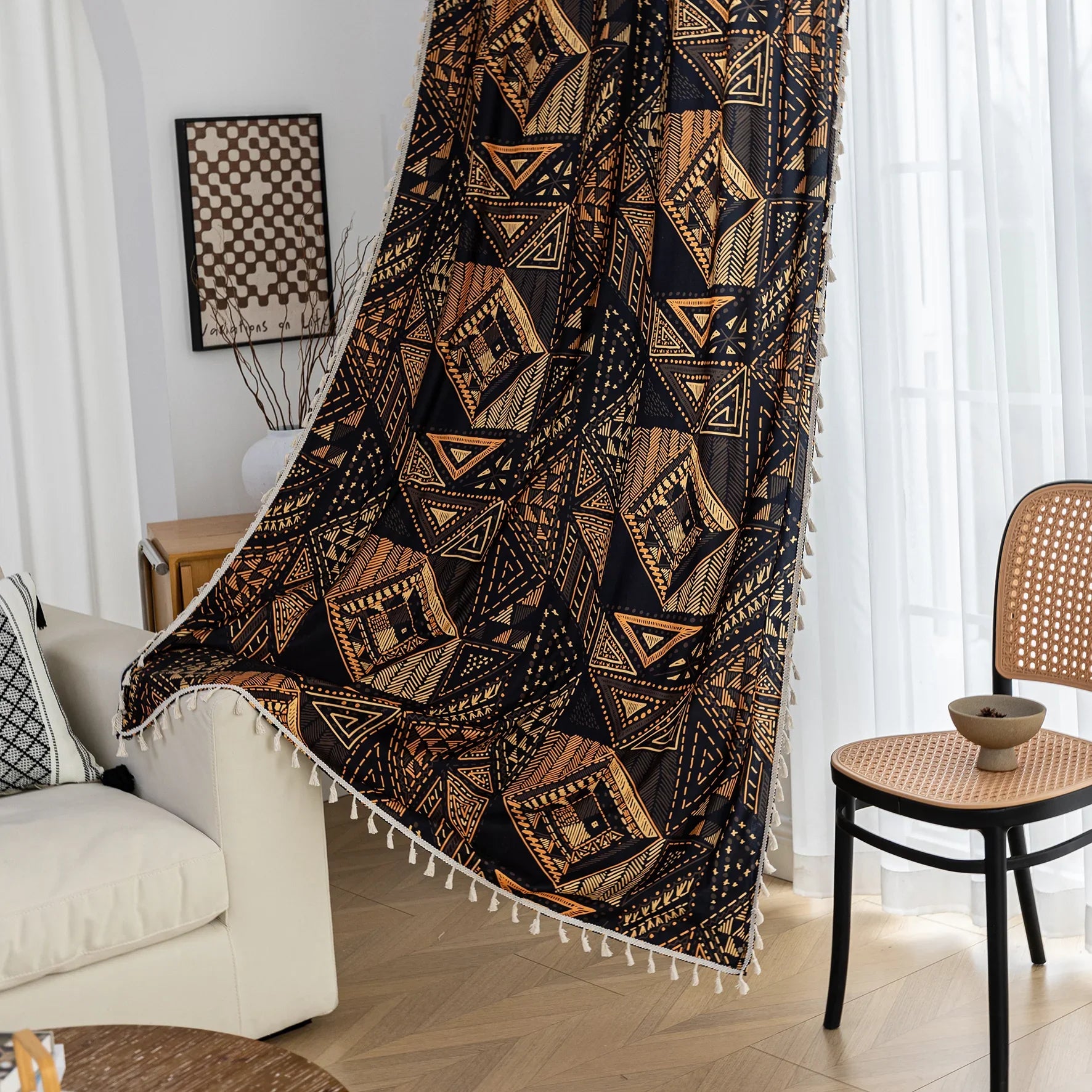 Stylish ethnic-inspired curtain with bold geometric patterns in warm golden-orange tones on a deep black background, accented with delicate tassel trim — ideal for adding a modern tribal touch and cozy elegance to your living space.