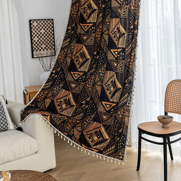 Stylish ethnic-inspired curtain with bold geometric patterns in warm golden-orange tones on a deep black background, accented with delicate tassel trim — ideal for adding a modern tribal touch and cozy elegance to your living space.