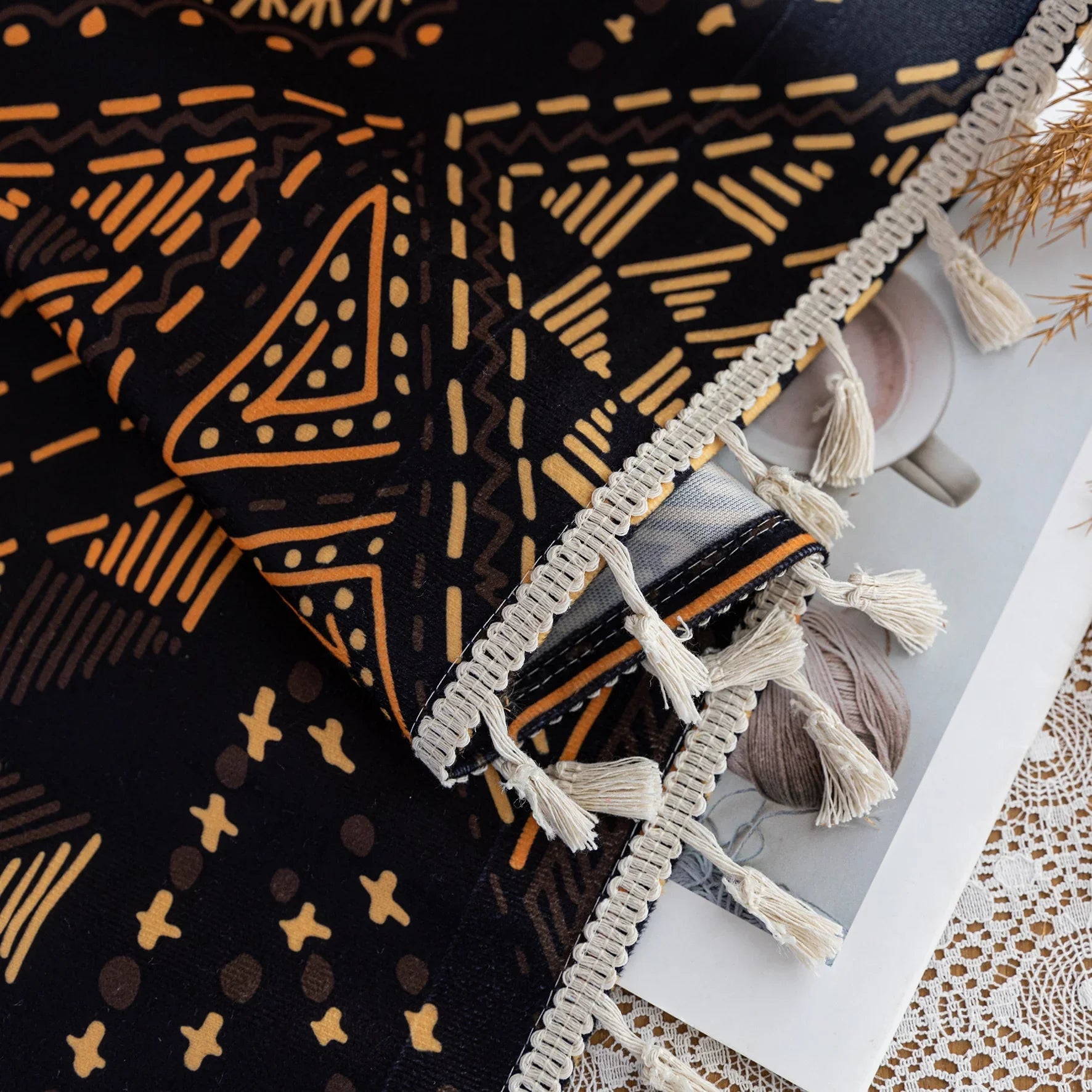 Stylish ethnic-inspired curtain with bold geometric patterns in warm golden-orange tones on a deep black background, accented with delicate tassel trim — ideal for adding a modern tribal touch and cozy elegance to your living space.