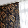 Stylish ethnic-inspired curtain with bold geometric patterns in warm golden-orange tones on a deep black background, accented with delicate tassel trim — ideal for adding a modern tribal touch and cozy elegance to your living space.