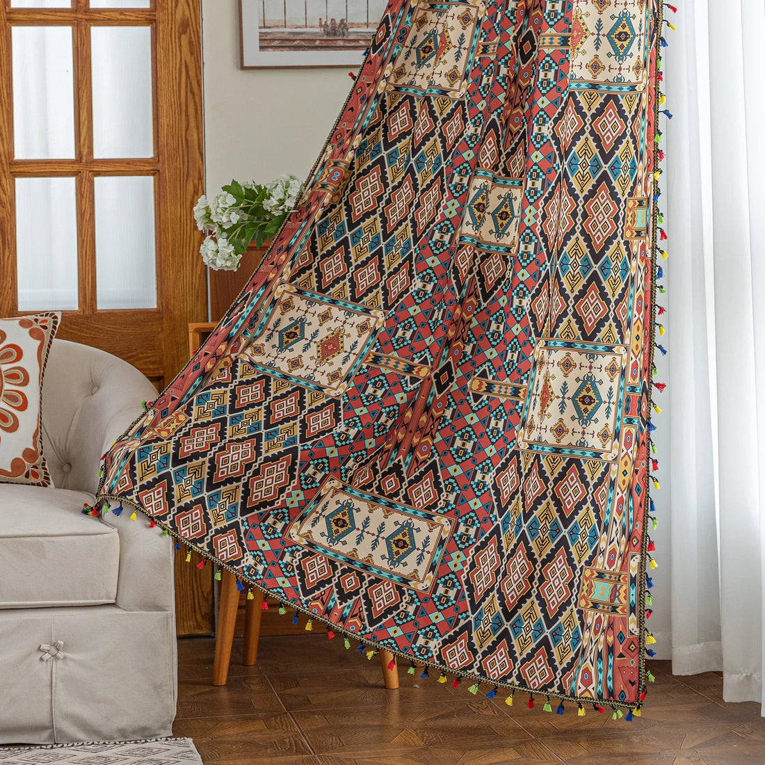 Colorful bohemian curtain with intricate tribal geometric patterns in rich earthy tones of red, beige, turquoise, and gold, accented with multicolor tassels — a perfect choice to add warmth, texture, and global-inspired charm to any room décor.