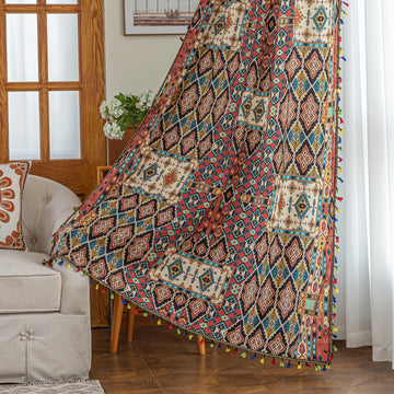 Colorful bohemian curtain with intricate tribal geometric patterns in rich earthy tones of red, beige, turquoise, and gold, accented with multicolor tassels — a perfect choice to add warmth, texture, and global-inspired charm to any room décor.