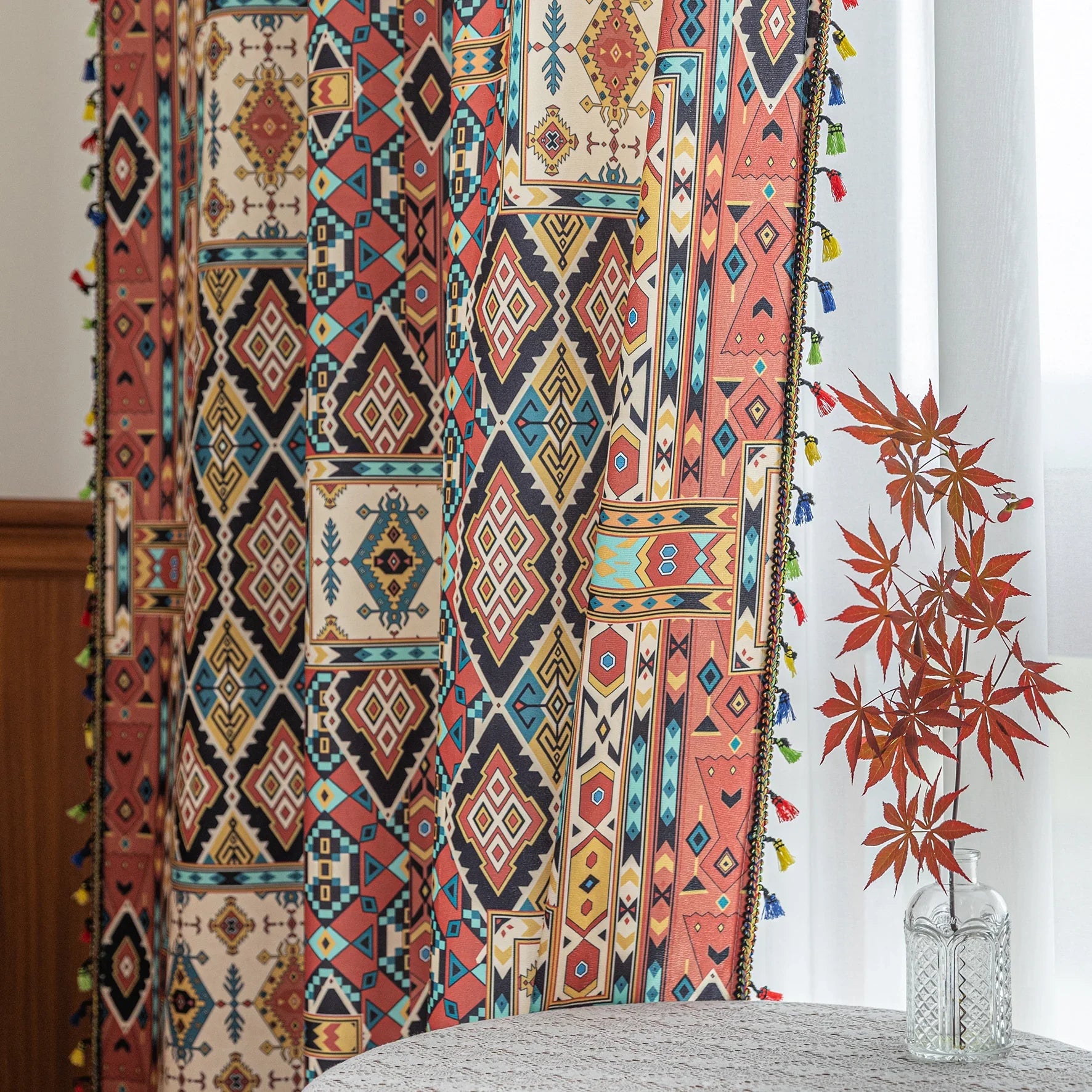 Colorful bohemian curtain with intricate tribal geometric patterns in rich earthy tones of red, beige, turquoise, and gold, accented with multicolor tassels — a perfect choice to add warmth, texture, and global-inspired charm to any room décor.