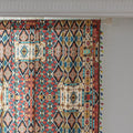 Colorful bohemian curtain with intricate tribal geometric patterns in rich earthy tones of red, beige, turquoise, and gold, accented with multicolor tassels — a perfect choice to add warmth, texture, and global-inspired charm to any room décor.