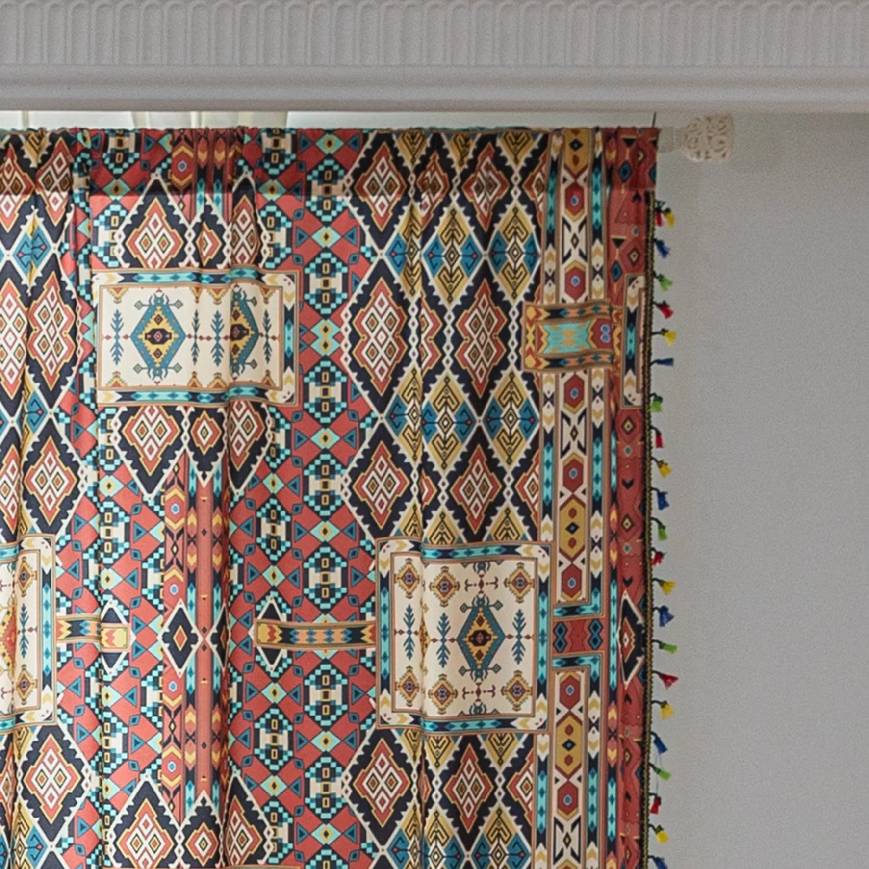 Colorful bohemian curtain with intricate tribal geometric patterns in rich earthy tones of red, beige, turquoise, and gold, accented with multicolor tassels — a perfect choice to add warmth, texture, and global-inspired charm to any room décor.