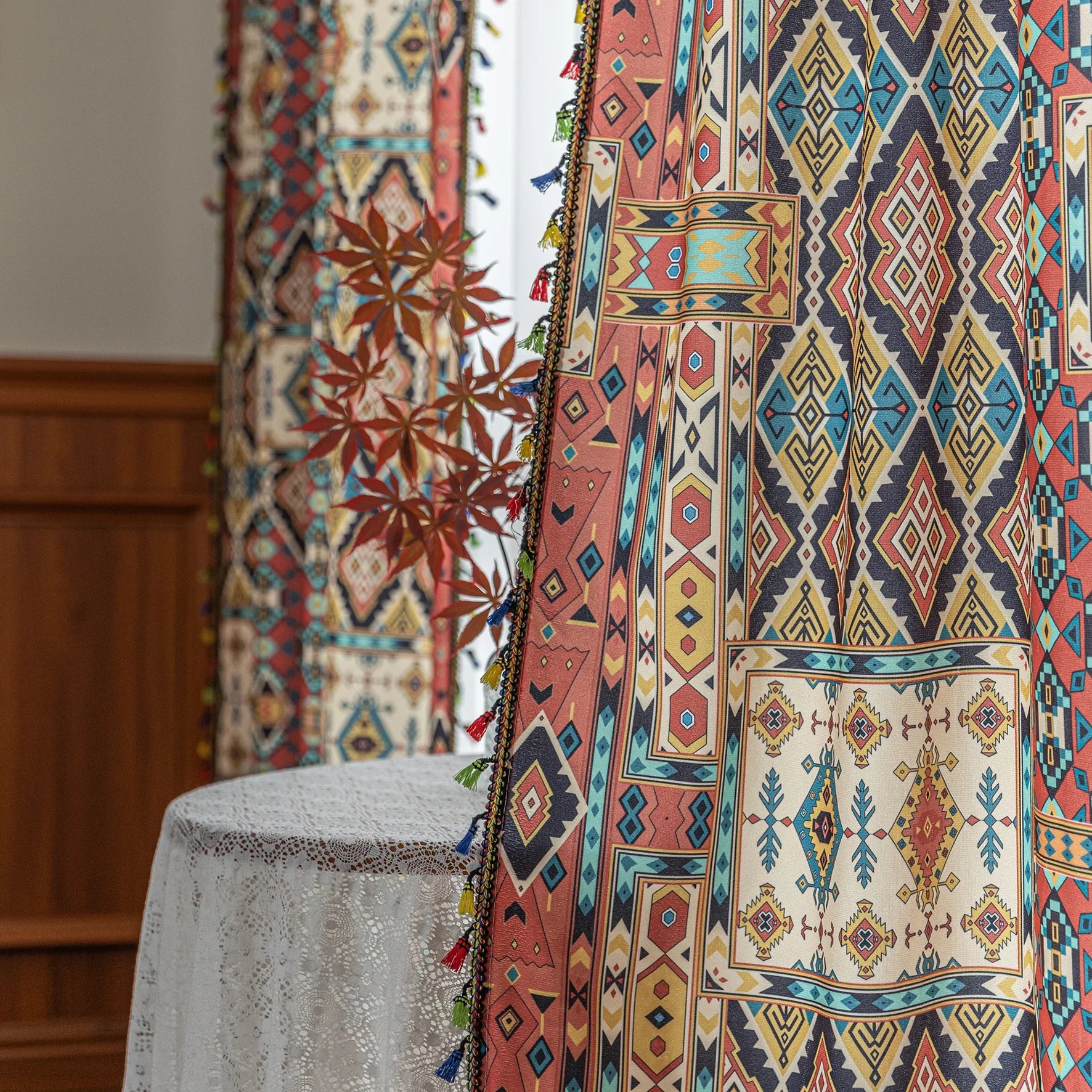 Colorful bohemian curtain with intricate tribal geometric patterns in rich earthy tones of red, beige, turquoise, and gold, accented with multicolor tassels — a perfect choice to add warmth, texture, and global-inspired charm to any room décor.