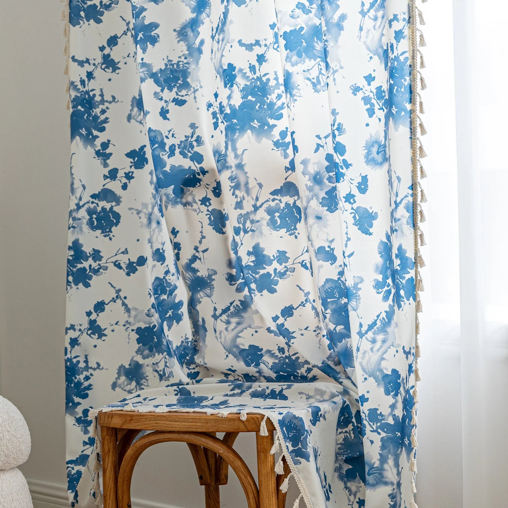 Elegant white curtain with soft watercolor-style blue floral prints, finished with delicate tassel trim — perfect for adding a fresh, airy, and romantic touch to your living room, bedroom, or cozy reading nook.