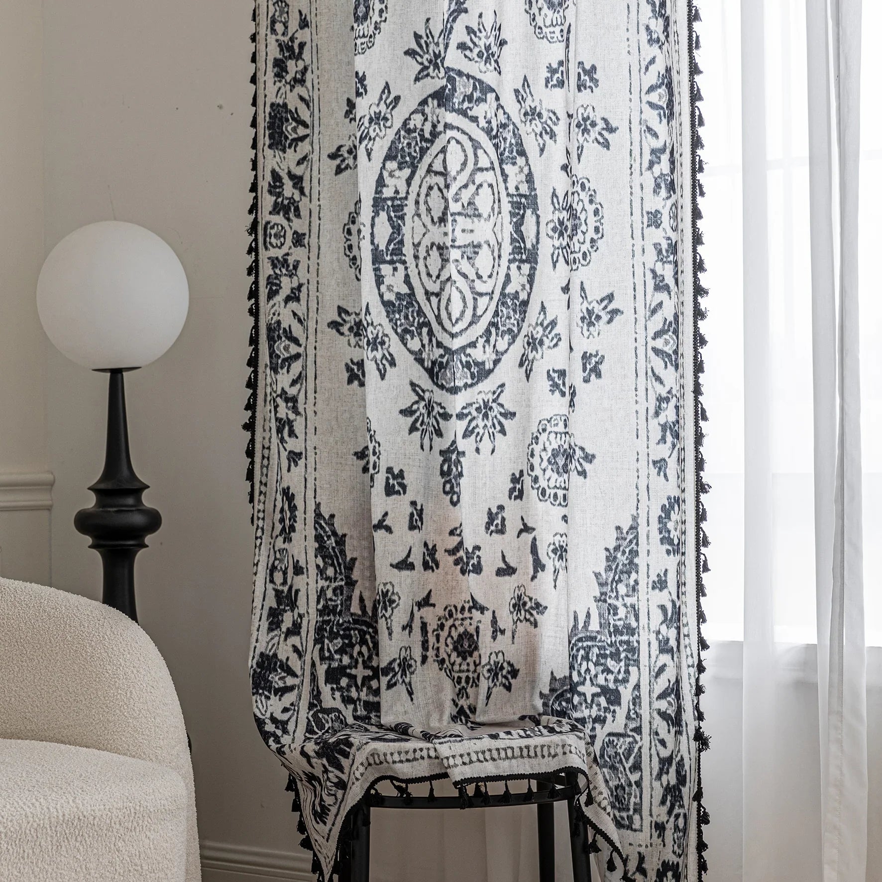 Elegant bohemian curtain in soft beige with intricate black floral and medallion motifs, finished with delicate black tassel trim — perfect for adding vintage charm and artistic flair to living rooms, bedrooms, or creative spaces.
