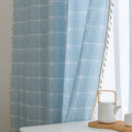 Sky blue curtain with a delicate white grid pattern and tassel trim — a stylish and airy window treatment that brightens your space while adding a modern, cozy touch.