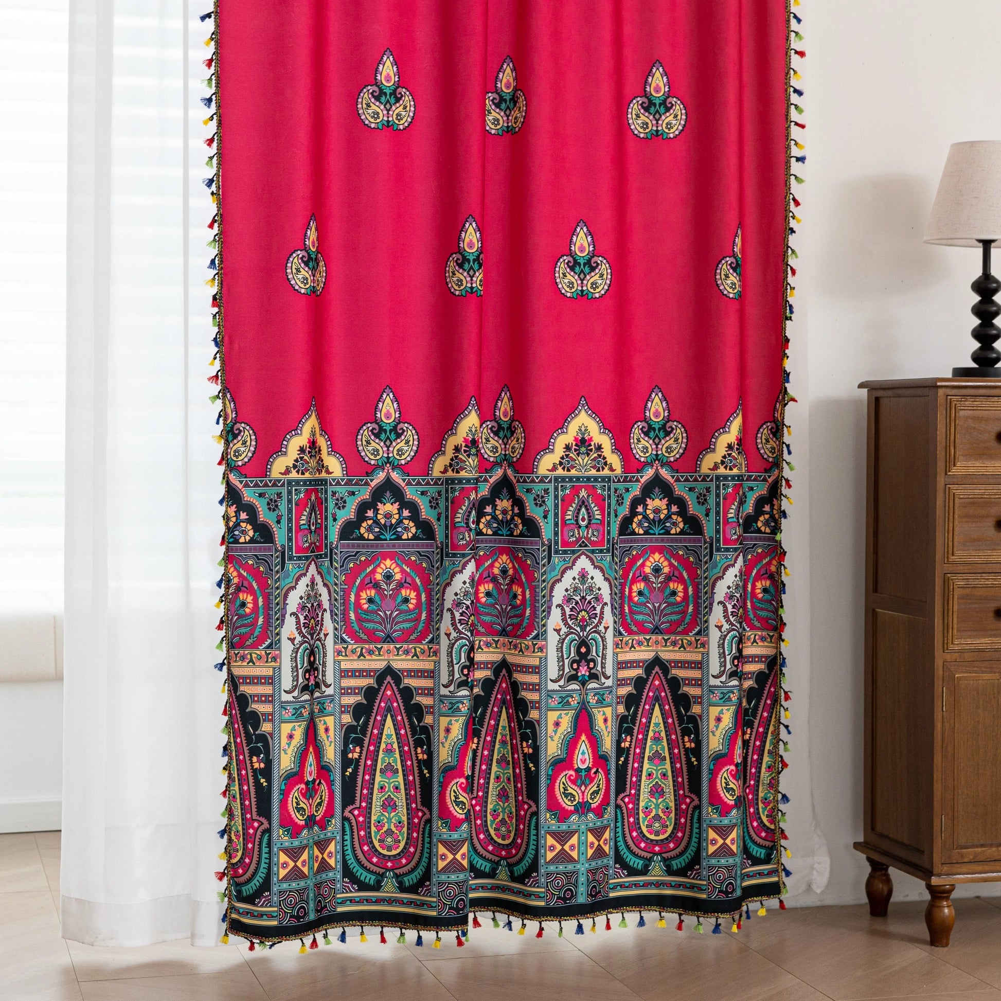 Vibrant Red Bohemian Curtains – Infuse your home with bold color and artistic flair using these stunning red curtains adorned with intricate multicolor ethnic patterns. The rich crimson backdrop is complemented by an elaborate border design in green, gold, and black, with small paisley-style motifs scattered throughout. Crafted from lightweight fabric, they softly filter sunlight while adding a warm, inviting atmosphere to any room. Perfect for living rooms, bedrooms, or creative spaces, these tassel-trimme
