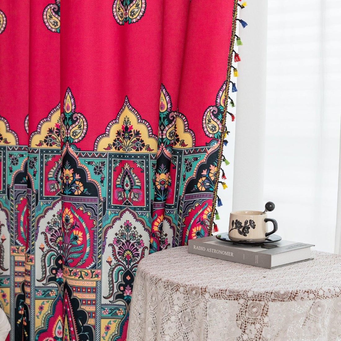 Vibrant Red Bohemian Curtains – Infuse your home with bold color and artistic flair using these stunning red curtains adorned with intricate multicolor ethnic patterns. The rich crimson backdrop is complemented by an elaborate border design in green, gold, and black, with small paisley-style motifs scattered throughout. Crafted from lightweight fabric, they softly filter sunlight while adding a warm, inviting atmosphere to any room. Perfect for living rooms, bedrooms, or creative spaces, these tassel-trimme