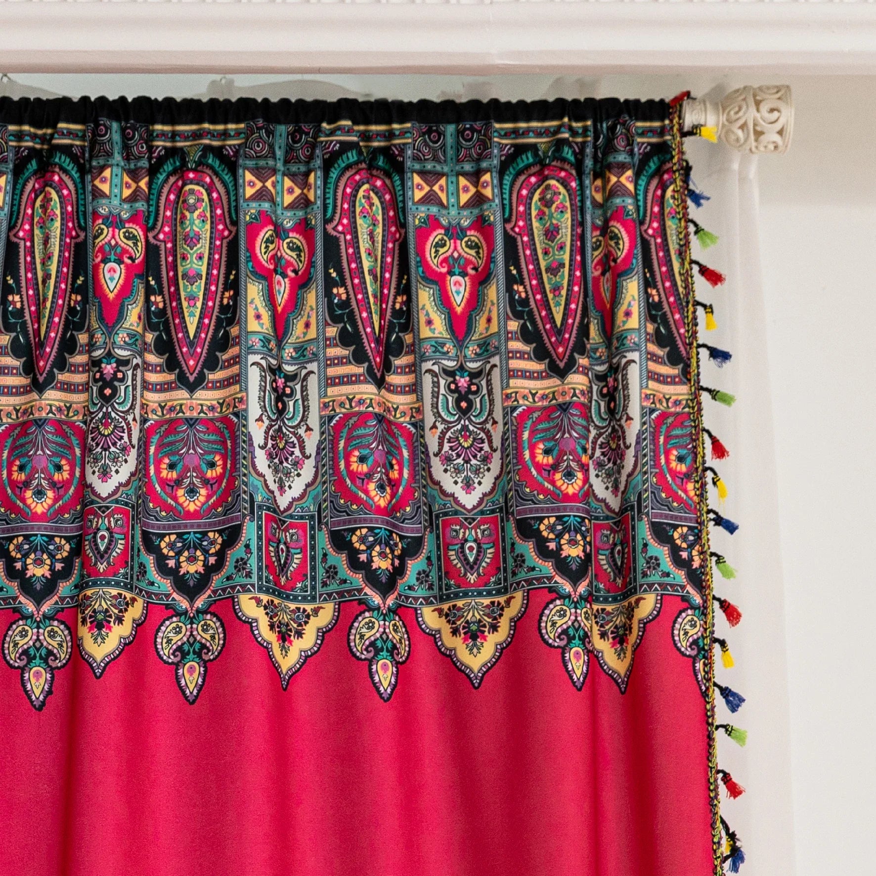 Vibrant Red Bohemian Curtains – Infuse your home with bold color and artistic flair using these stunning red curtains adorned with intricate multicolor ethnic patterns. The rich crimson backdrop is complemented by an elaborate border design in green, gold, and black, with small paisley-style motifs scattered throughout. Crafted from lightweight fabric, they softly filter sunlight while adding a warm, inviting atmosphere to any room. Perfect for living rooms, bedrooms, or creative spaces, these tassel-trimme
