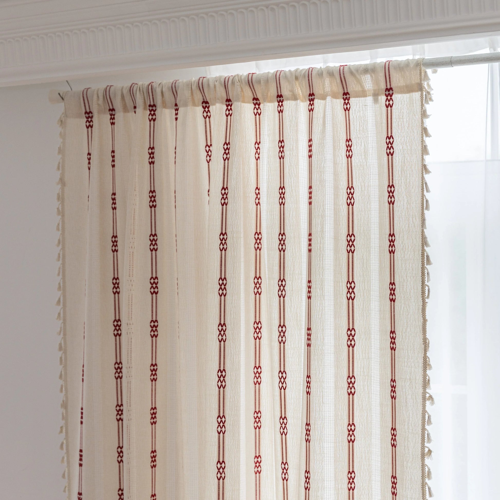 Elegant white curtain with vertical red embroidered stripes and subtle tassel edging — perfect for adding a touch of sophistication and warmth to your living room or bedroom décor.