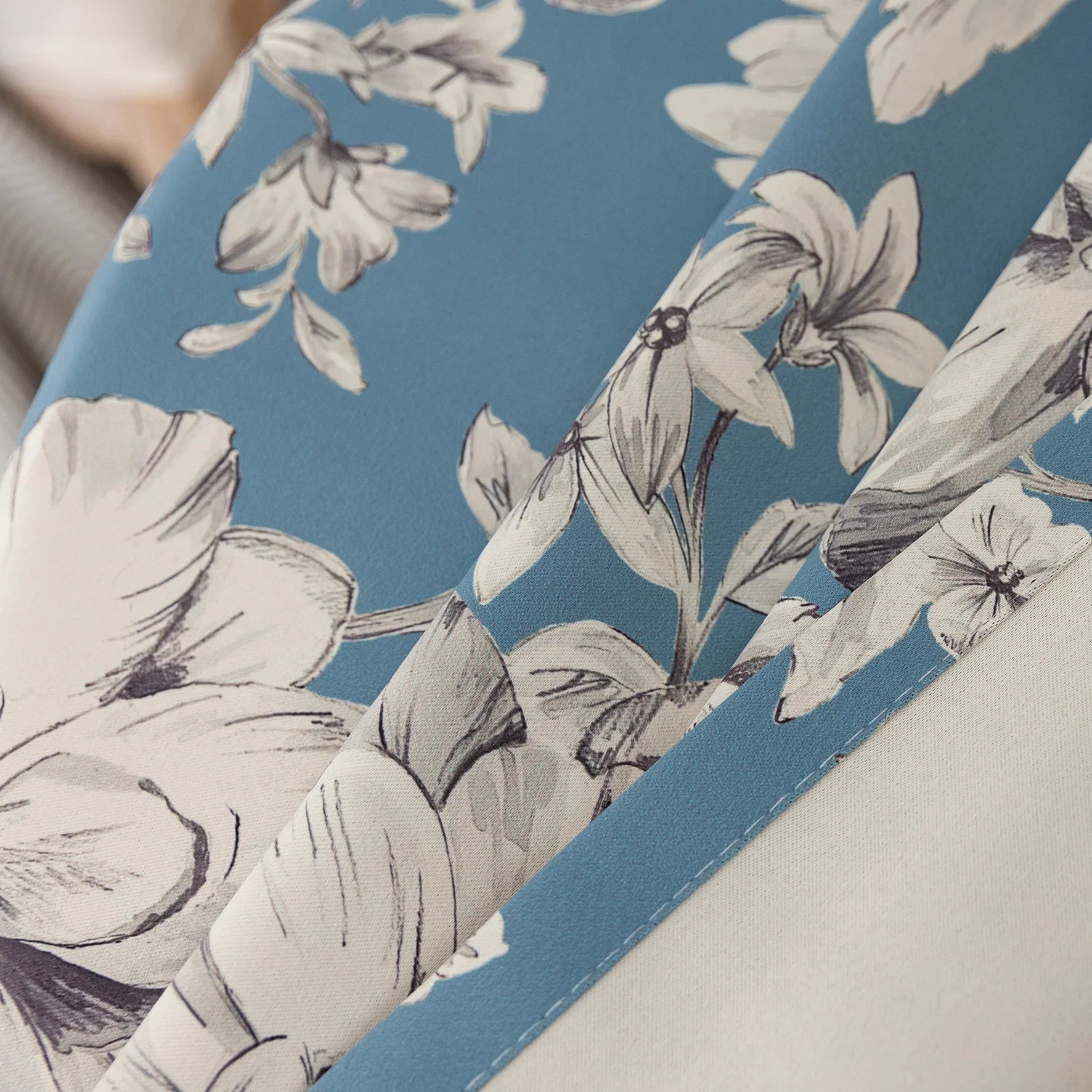 Elegant floral blackout curtain featuring soft cream blossoms on a serene blue background, combining classic botanical charm with effective light-blocking for a cozy and stylish living space.