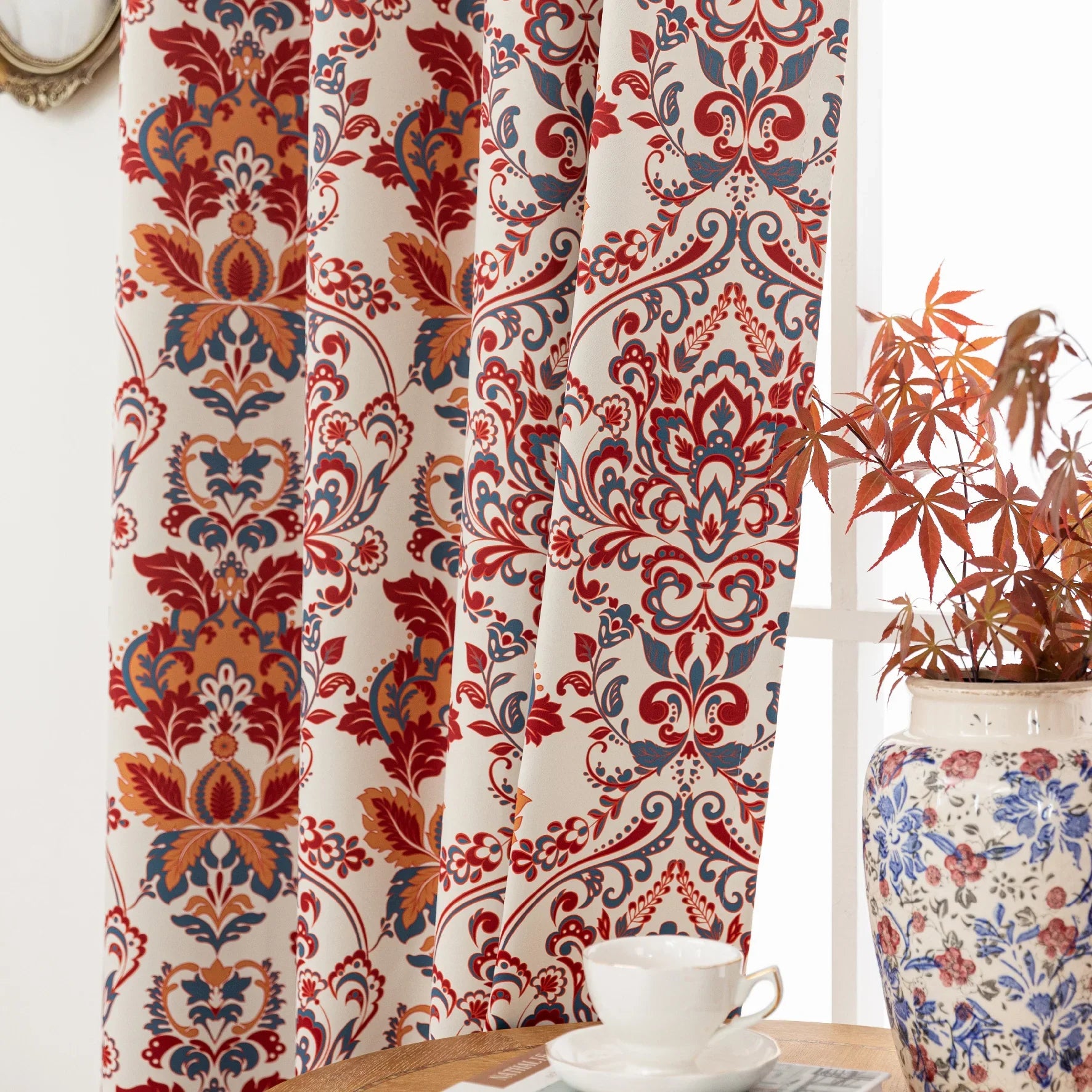 Vibrant blackout curtain featuring an intricate red, orange, and blue damask floral pattern on a soft cream background, designed to block light, enhance privacy, and add a bold, elegant touch to any room décor.