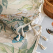 Close-up of beige sheer curtain with colorful floral and leafy pattern, decorated with delicate tassel trim, creating an elegant and airy botanical look for home interiors.